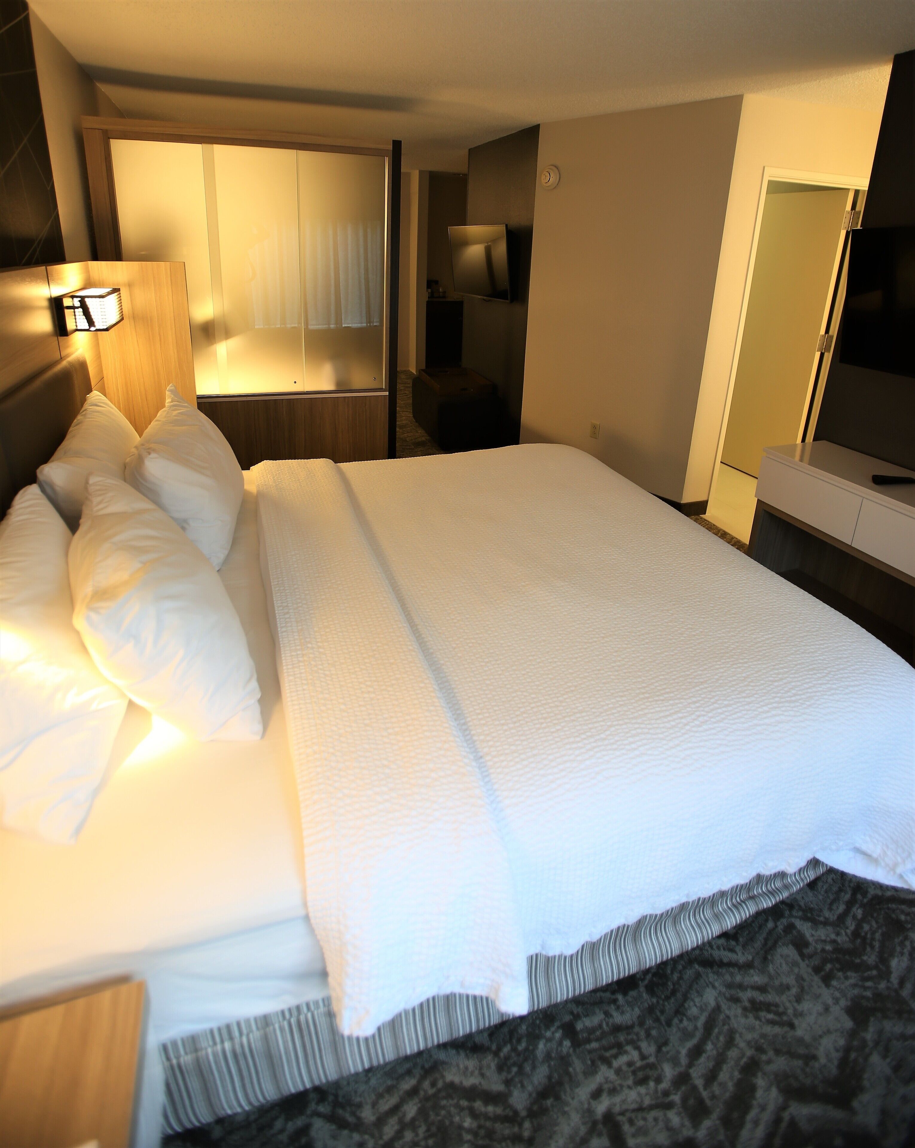 A hotel room with a large bed, a bedside table, a TV, and a wardrobe.