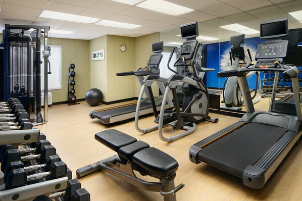 Un gimnasio con cintas de correr, elípticas y pesas sueltas.