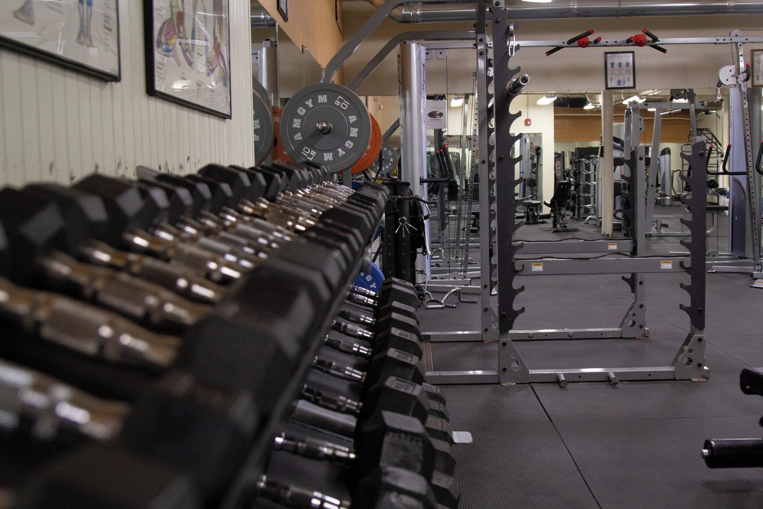 A gym with weightlifting equipment, a mirror, and exercise machines.