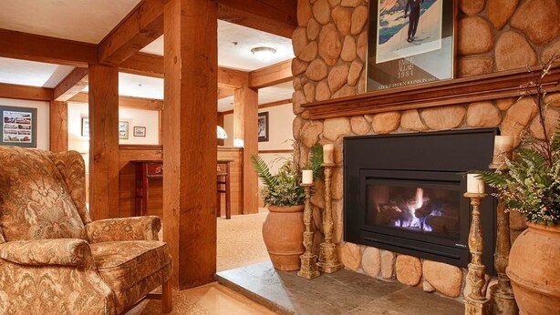 A cozy living room with a stone fireplace, a comfortable armchair, and a framed picture above the fireplace.