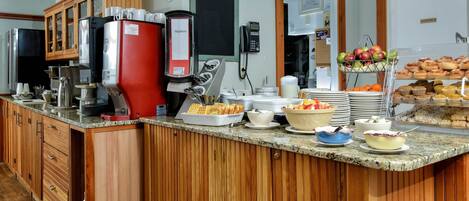 A buffet setup with various food items and a coffee station.