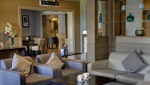 A modern hotel lobby with grey sofas, a coffee table, and a reception desk. - Crowne Plaza East Midlands Airport by IHG (Kegworth)