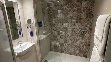 A modern bathroom with a glass-enclosed shower, a sink, and a mirror.