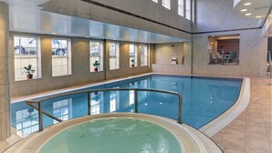 An indoor swimming pool with a hot tub, large windows, and a seating area with tables and chairs. - Crowne Plaza East Midlands Airport by IHG (Kegworth)