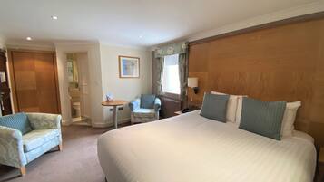 Une chambre d’hôtel avec un grand lit, une petite table, une chaise et une armoire.