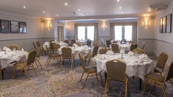 A conference room with round tables, chairs, and wall sconces.