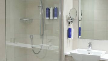 A modern bathroom with a glass-enclosed shower, a white sink, and a mirror above it.