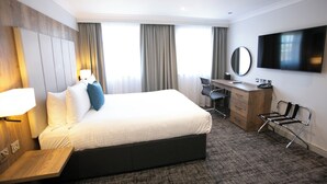 A hotel room with a large bed, a desk with a chair, a TV, and a window with curtains. - Crowne Plaza East Midlands Airport by IHG (Kegworth)