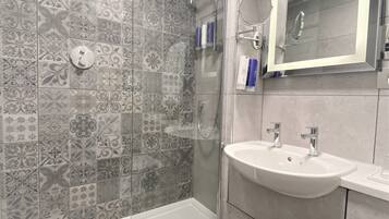 A modern bathroom with a glass-enclosed shower, a white bathtub, and a vanity with a mirror.