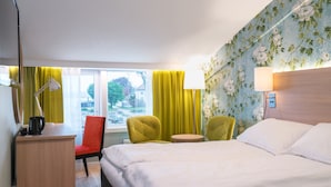 A hotel room with a bed, a desk with a lamp, two chairs, a small table, and a view of the outside through a window with curtains. - Thon Hotel Tønsberg Brygge (Tønsberg)