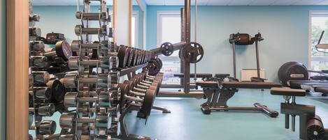A gym with various exercise equipment, including dumbbells, a squat rack, and a bench.