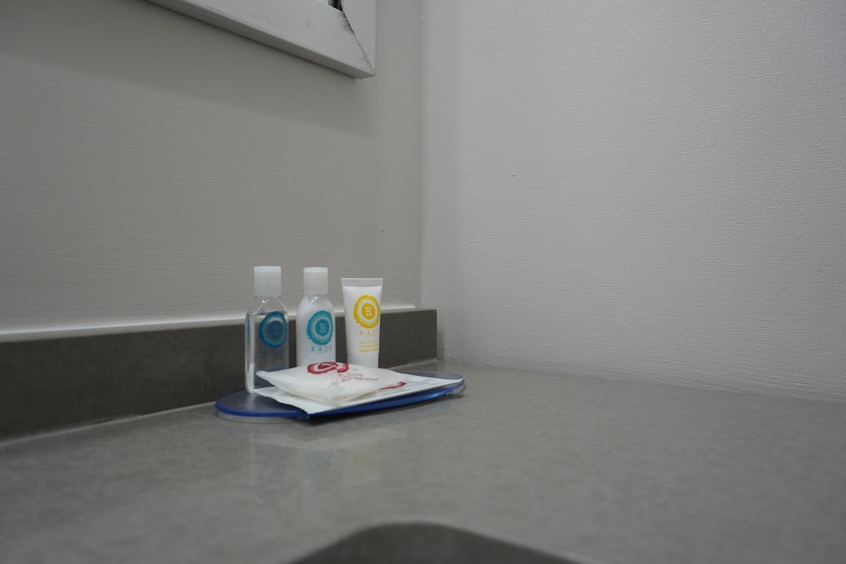 A bathroom counter with three bottles of hand sanitizer and a tissue box.