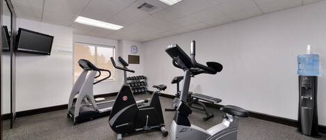 Un gimnasio con bicicletas estáticas, cintas de correr y mancuernas.