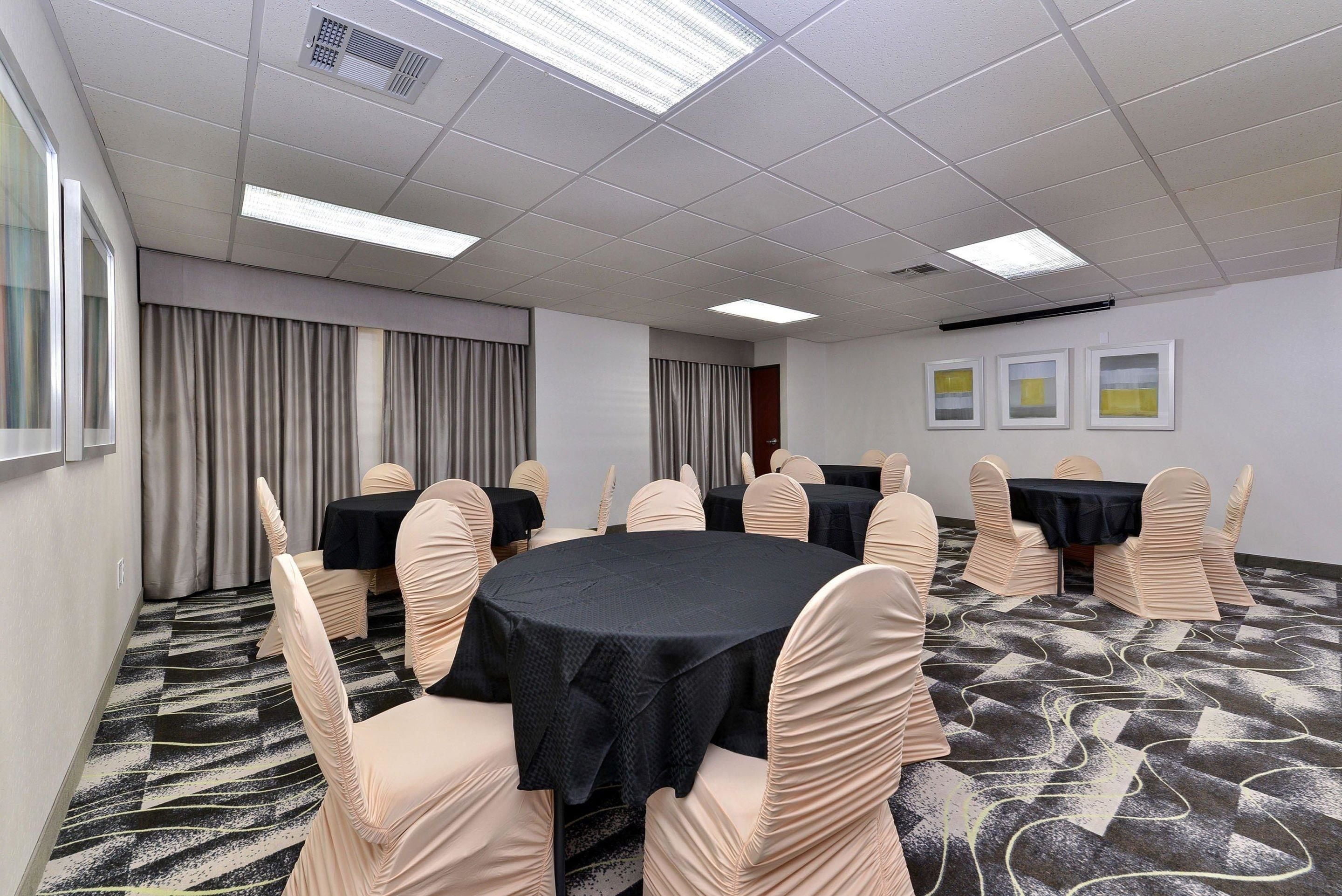 A conference room with round tables, beige chairs, and a patterned carpet.