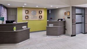 A reception area with two counters, a sign for Comfort Inn & Suites, and an elevator. - Comfort Inn & Suites Frisco - Plano (Frisco)
