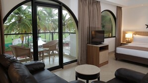 A hotel room with a balcony, a bed, a TV, a desk, and a sofa.