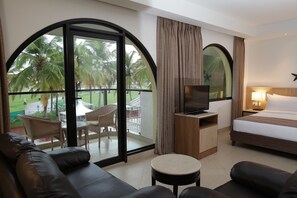 A hotel room with a balcony, a bed, a TV, a desk, and a sofa.