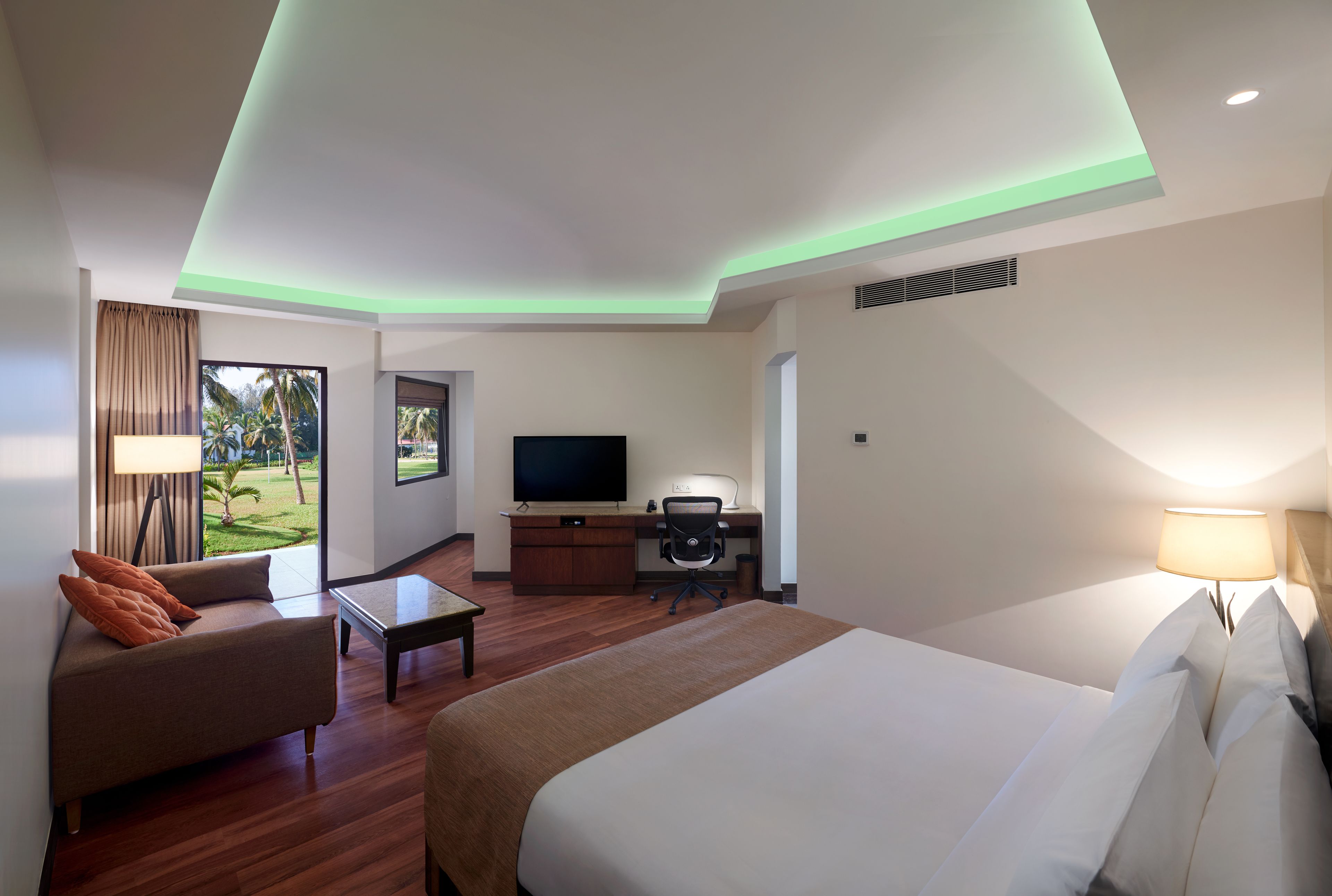 A hotel room with a bed, a desk, a TV, and a view of the outdoors.