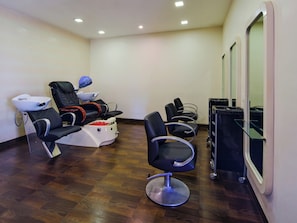 A room with a massage chair, a hair washing station, and a salon chair.