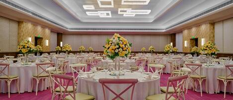 A large banquet hall with round tables, chairs, and floral centerpieces.