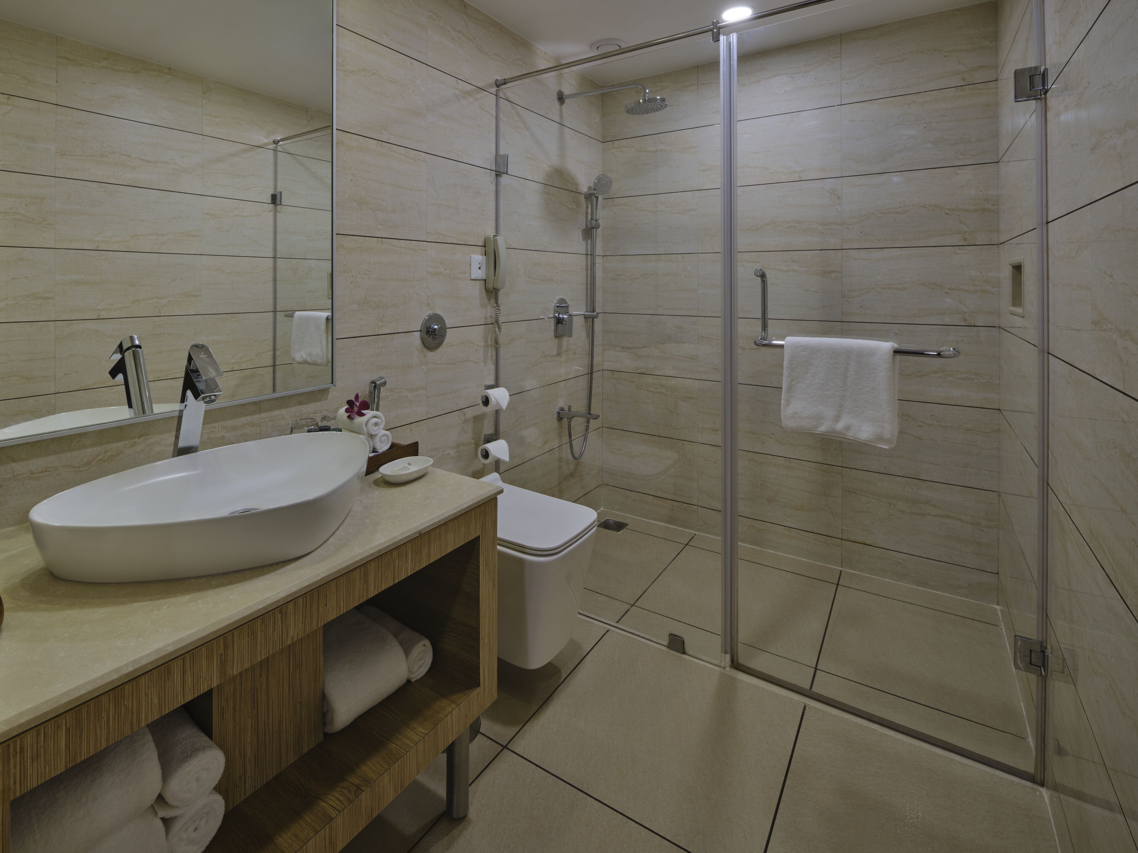 Un baño moderno con un lavamanos grande, inodoro y ducha con mampara de vidrio.