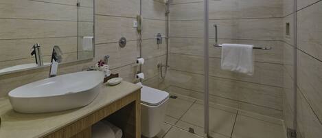 Un baño moderno con un lavamanos grande, inodoro y ducha con mampara de vidrio.