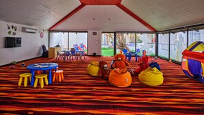 A spacious indoor play area with a high ceiling, colorful play equipment, and a large window offering a view of the outdoors. - Holiday Inn Resort Goa by IHG (Cavelossim)