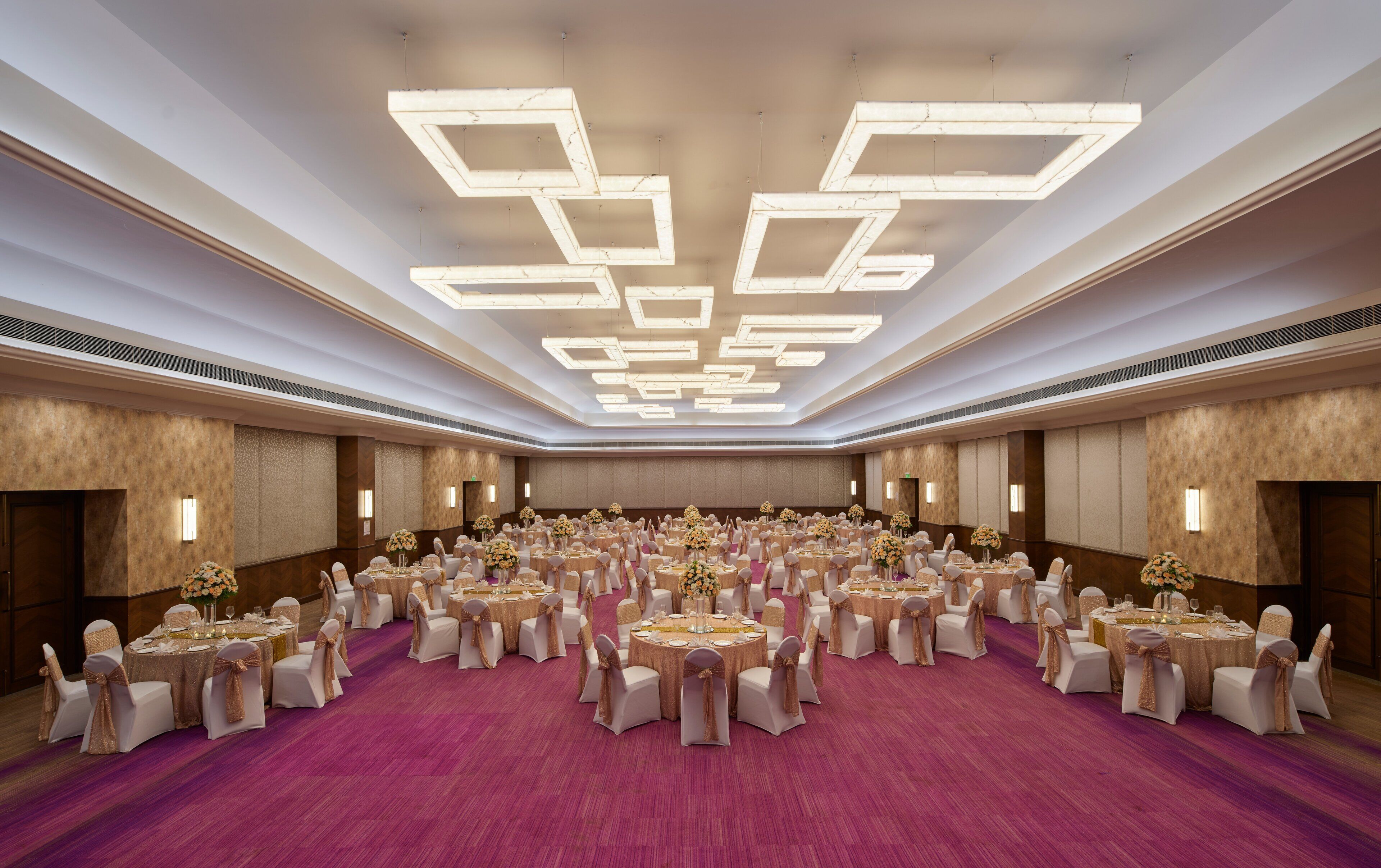 A large banquet hall with round tables, white chairs, and gold sashes.