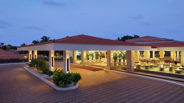 A hotel with a covered outdoor area, multiple columns, and a pool with lights.