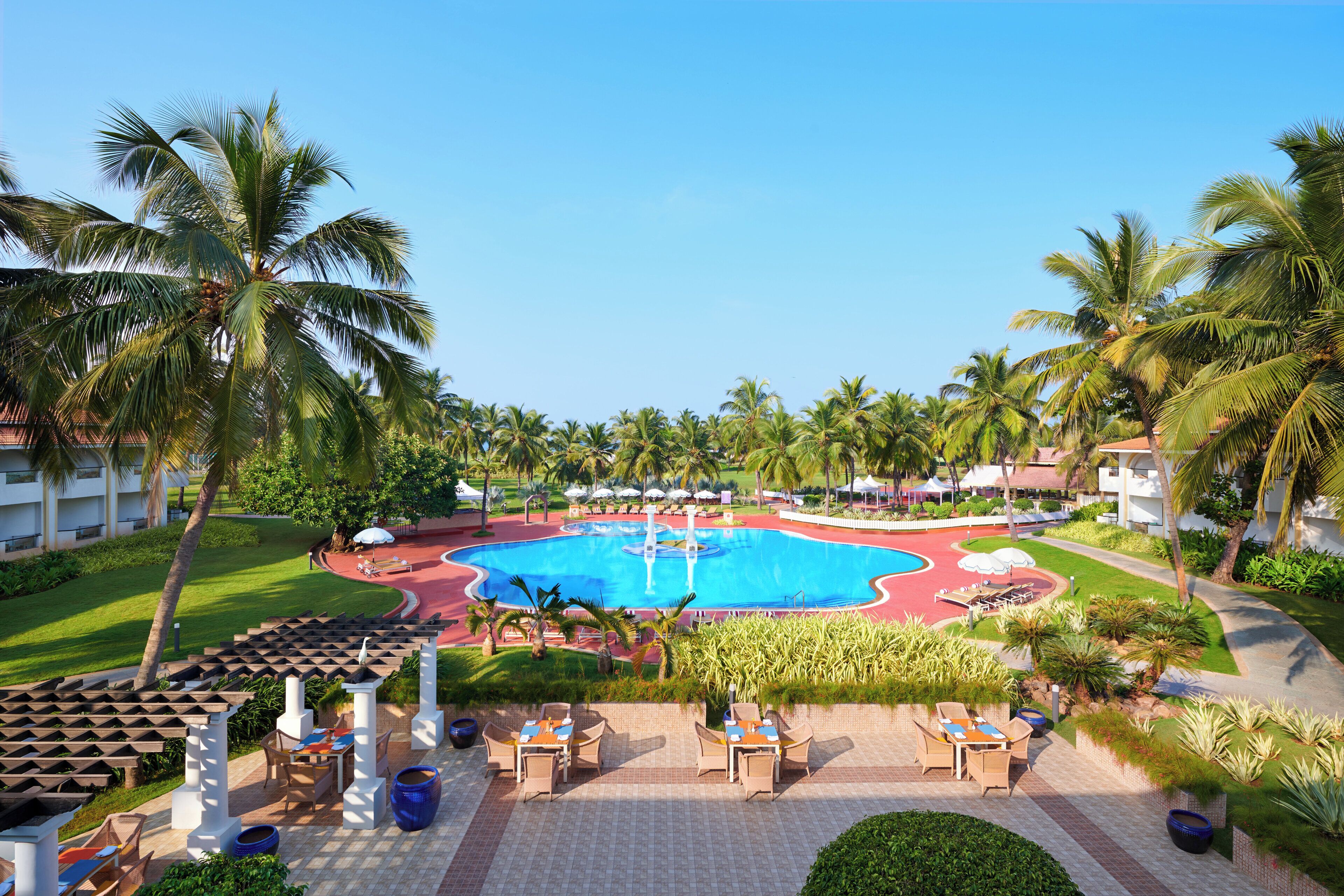 Resort com piscina central, áreas de estar ao ar livre e palmeiras.