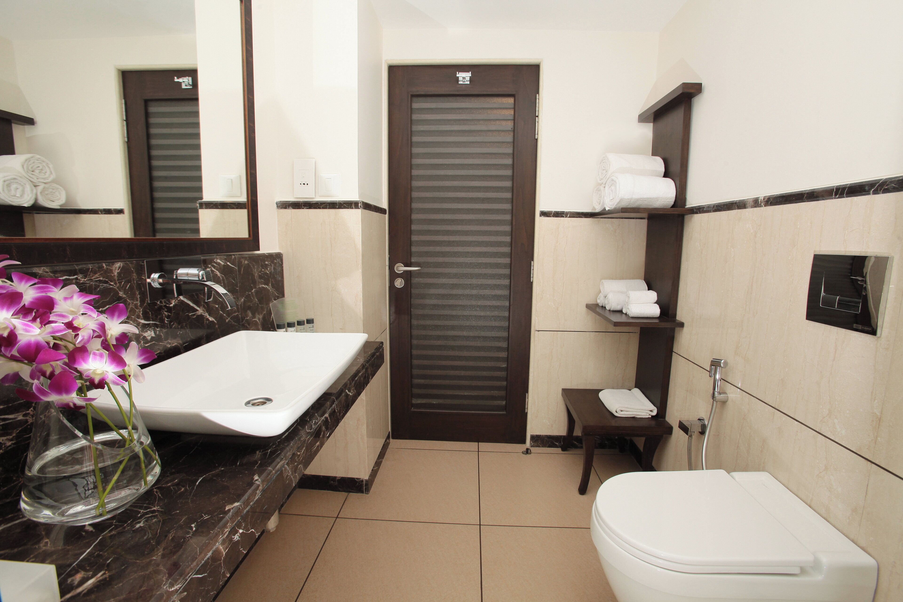 A bathroom with a marble sink, a toilet, a towel rack, and a mirror.