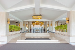 A spacious lobby with a central staircase, large columns, and potted plants. - Holiday Inn Resort Goa by IHG (Cavelossim)