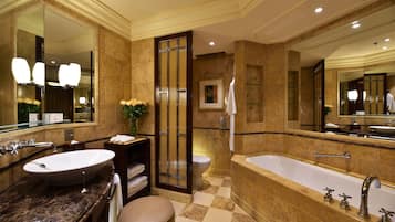 A luxurious bathroom with a large bathtub, two sinks, and a vanity with a mirror.
