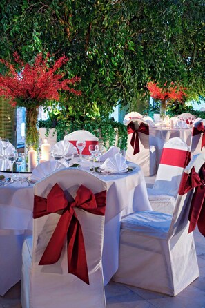 An outdoor dining area with round tables, white tablecloths, and red sashes on chairs. - The Hongta Hotel, a Luxury Collection Hotel, Shanghai (Shanghai)