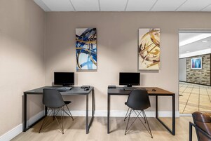Un espacio de oficina moderno con dos escritorios, cada uno con una computadora y una silla.