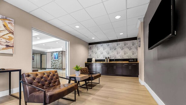 A modern interior with a seating area, a kitchen, and a large TV on the wall.