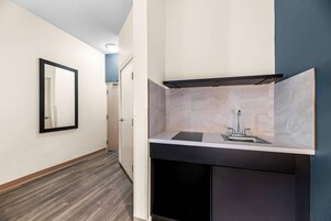 Un bagno moderno con specchio, lavandino e mobili contenitori scuri.