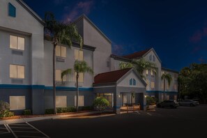 A multi-story hotel with a central entrance, large windows, and a parking area. - Suburban Studios Orlando - Ocoee/Winter Garden (Ocoee)