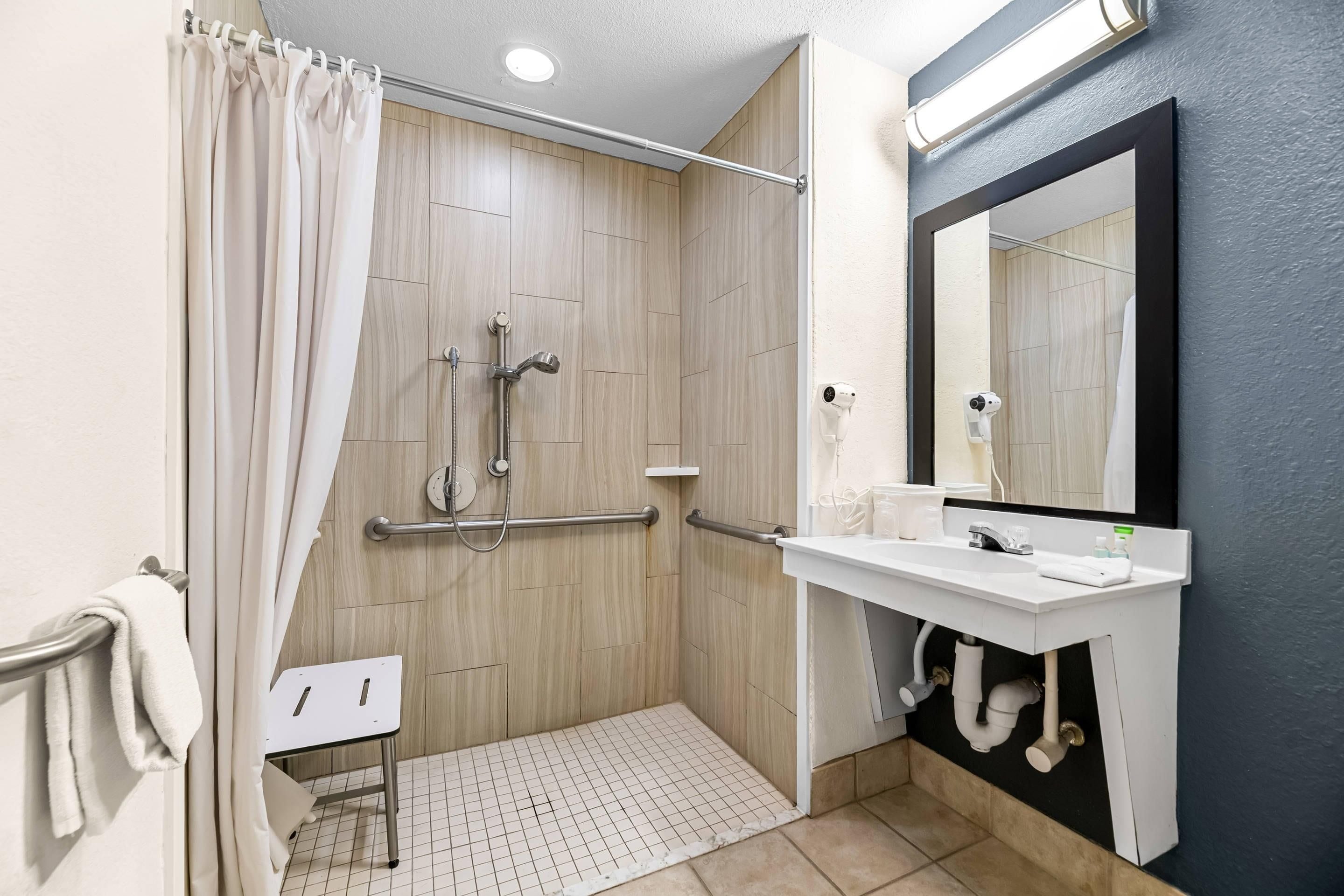 A modern bathroom with a shower, a white sink, and a mirror.