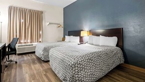 A hotel room with two beds, a desk, a chair, and a window with curtains.