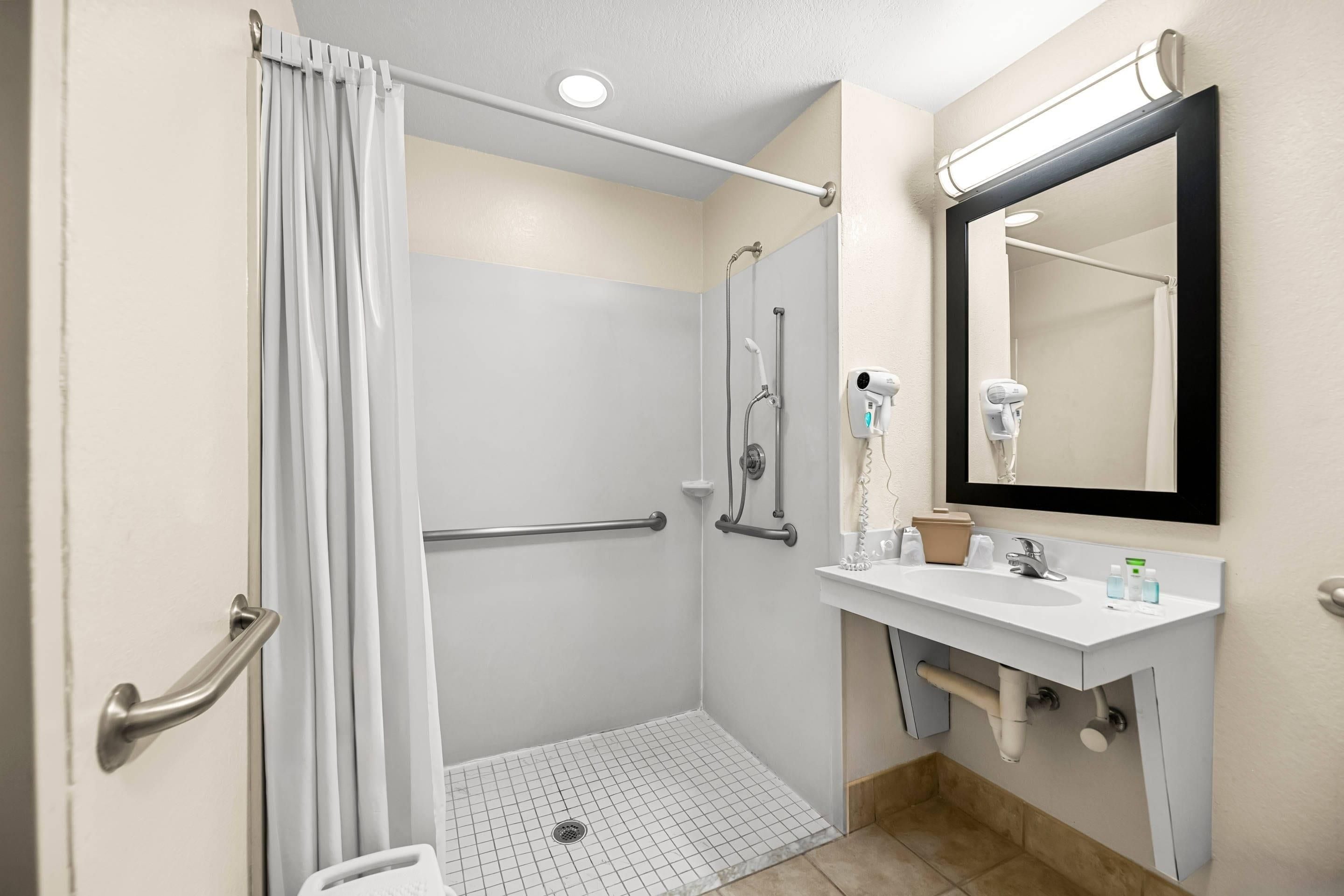 Une salle de bain avec une douche, un lavabo et un miroir.