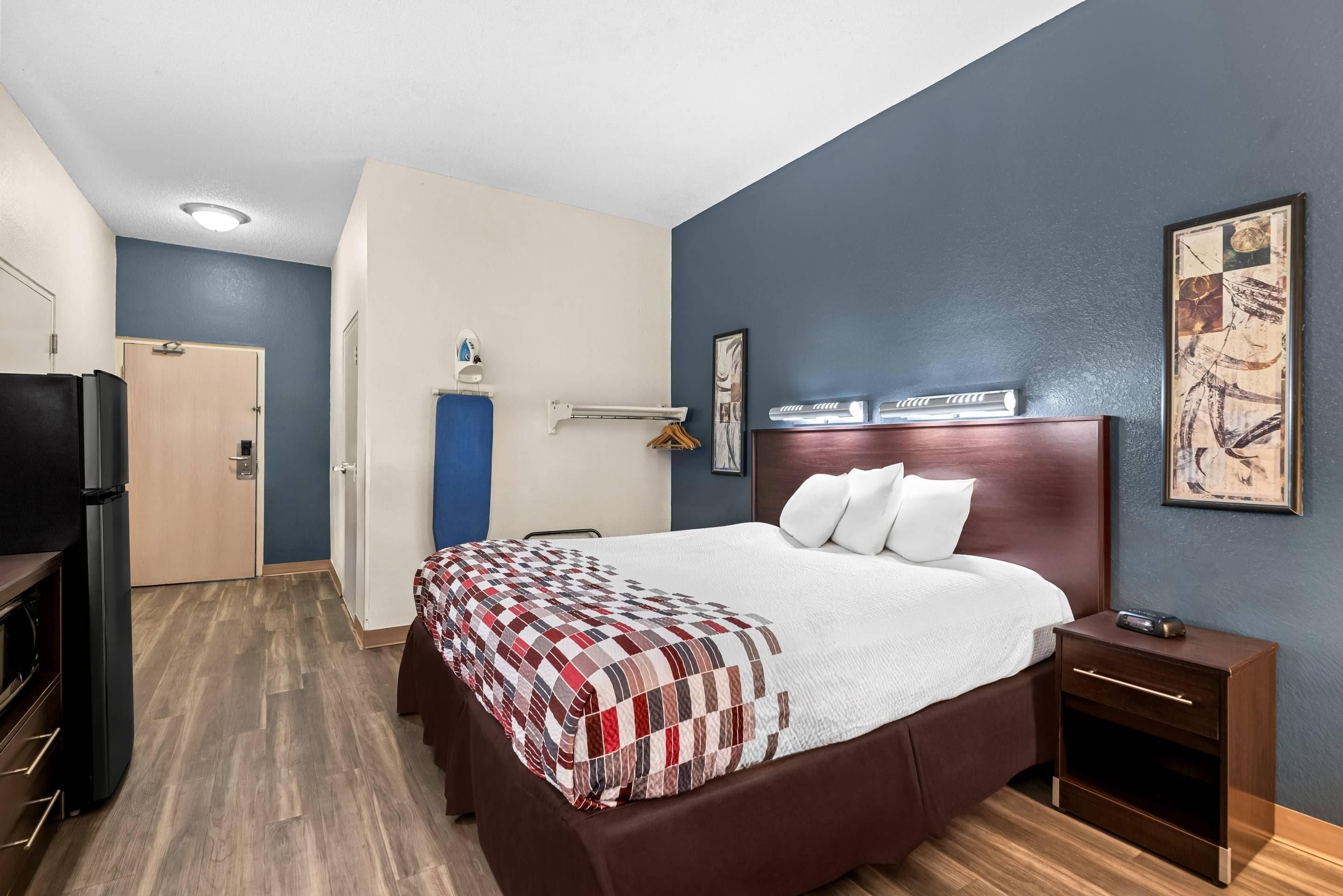 Een hotelkamer met een groot bed, nachtkastje, kledingkast en televisie.