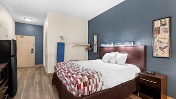 Een hotelkamer met een groot bed, nachtkastje, kledingkast en televisie.