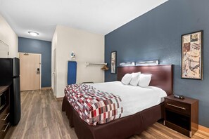 Una habitación de hotel con una cama grande, una mesita de noche, un armario y un televisor.