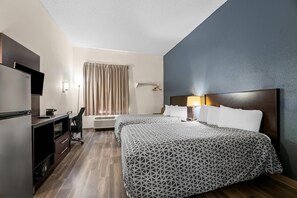 Une chambre d’hôtel avec deux lits, un bureau, une télévision et une fenêtre avec des rideaux.
