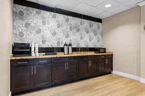 Una cocina moderna con armarios oscuros, encimera de granito y salpicadero con estampado floral.