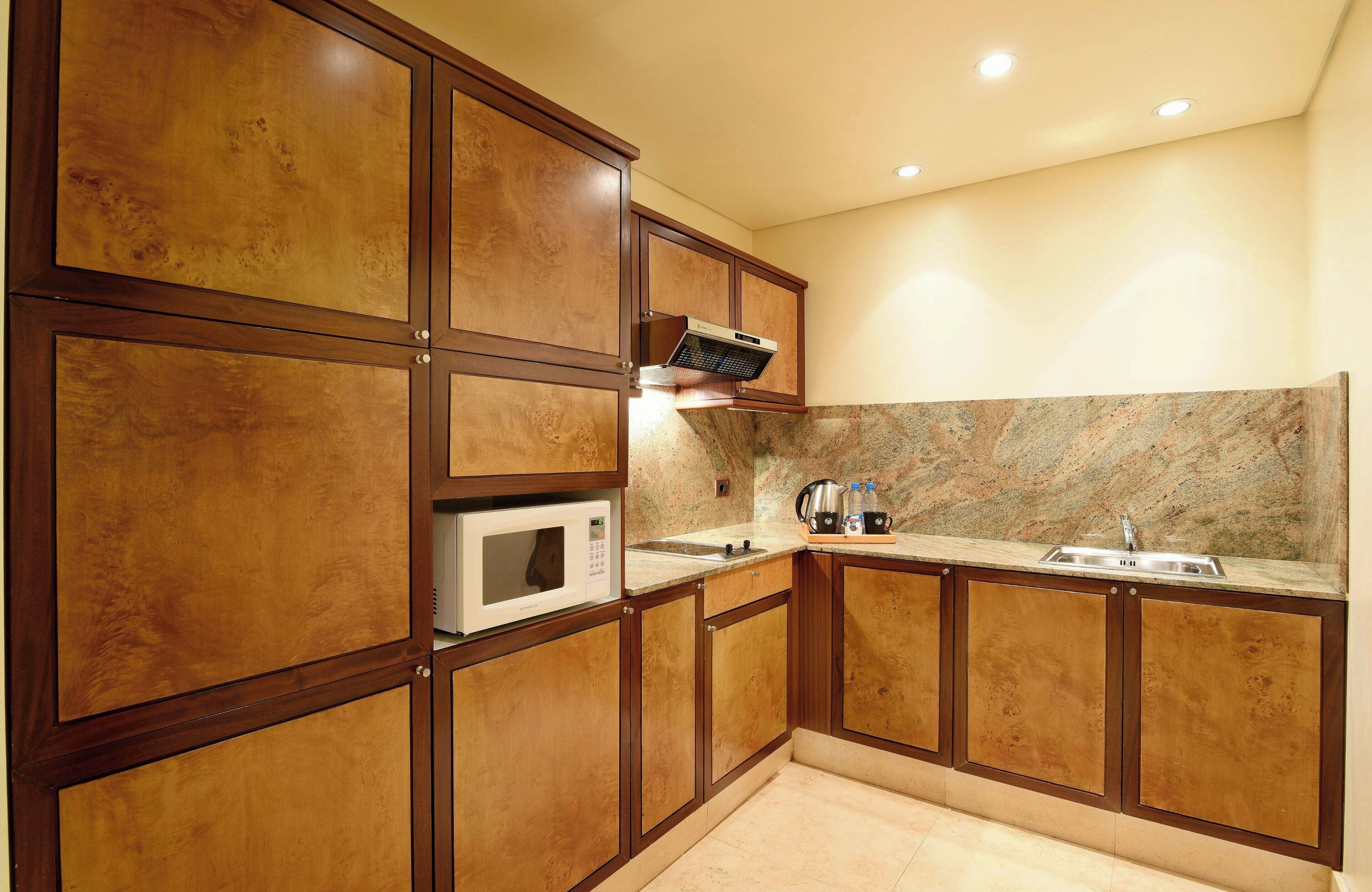 A kitchen with wooden cabinets, a microwave, a stove, and a granite countertop.