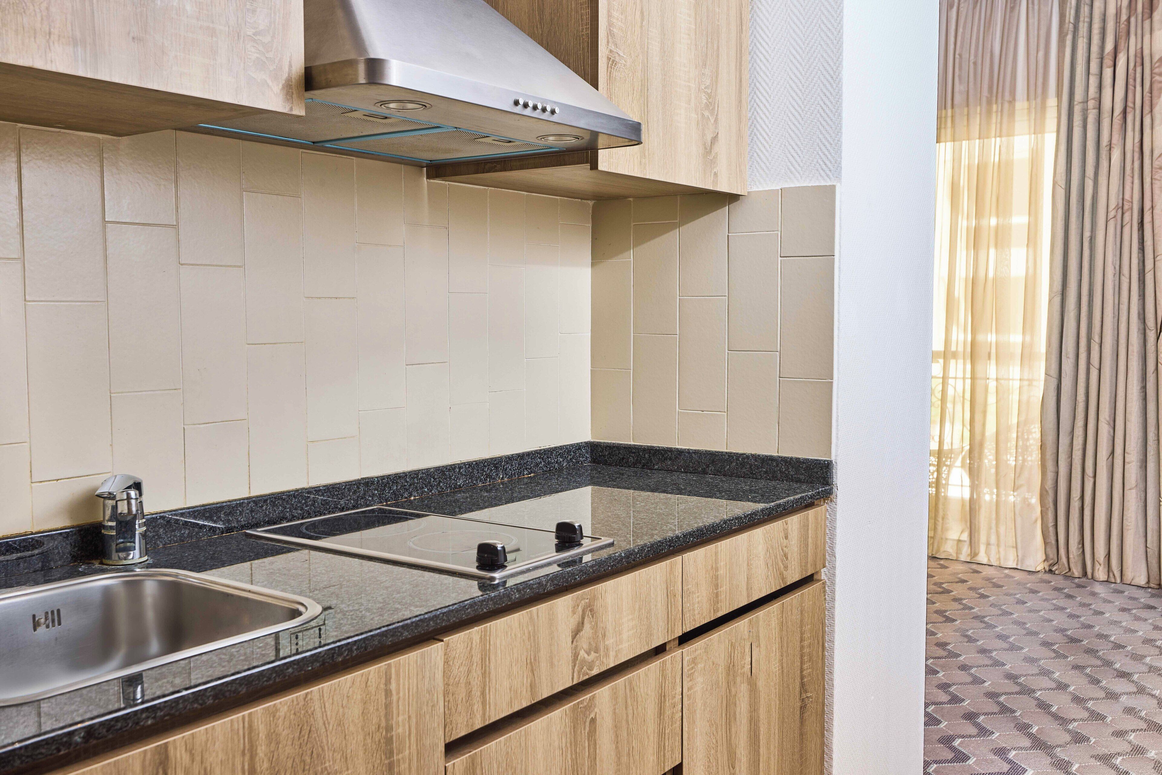 Eine moderne Küche mit Spüle aus Edelstahl, schwarzem Granitwerkstein und Holzschränken.