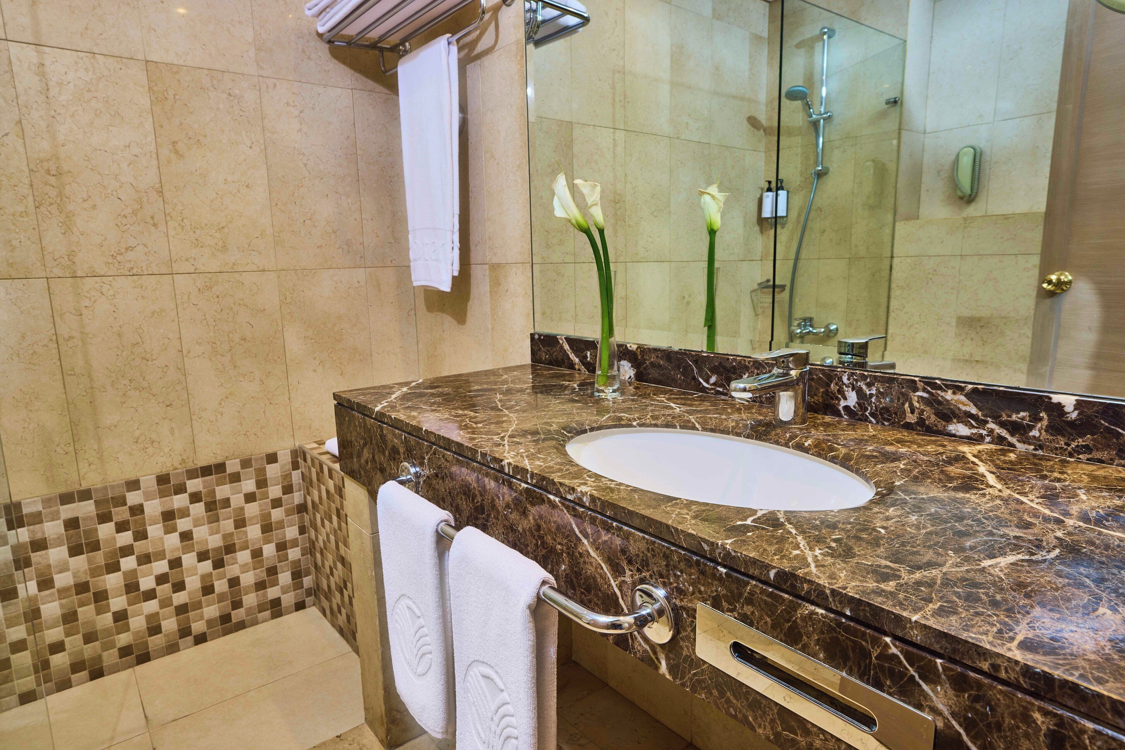 A bathroom with a marble sink, a glass shower enclosure, and a tiled shower area.