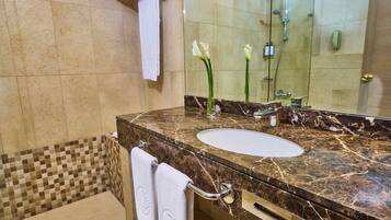 A bathroom with a marble sink, a glass shower enclosure, and a tiled shower area.